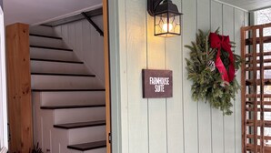 A staircase with a sign reading 'FARMHOUSE SUITE' and a decorative wreath with a red bow. - Red Fox Run B&B (Cazenovia)