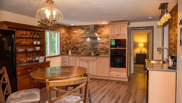 A kitchen with wooden cabinets, a dining table, and a chandelier. - Red Fox Run B&B (Cazenovia)