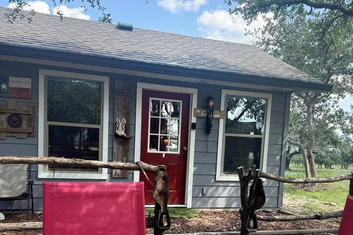 A house with a red door, a garage door, and a wooden fence.