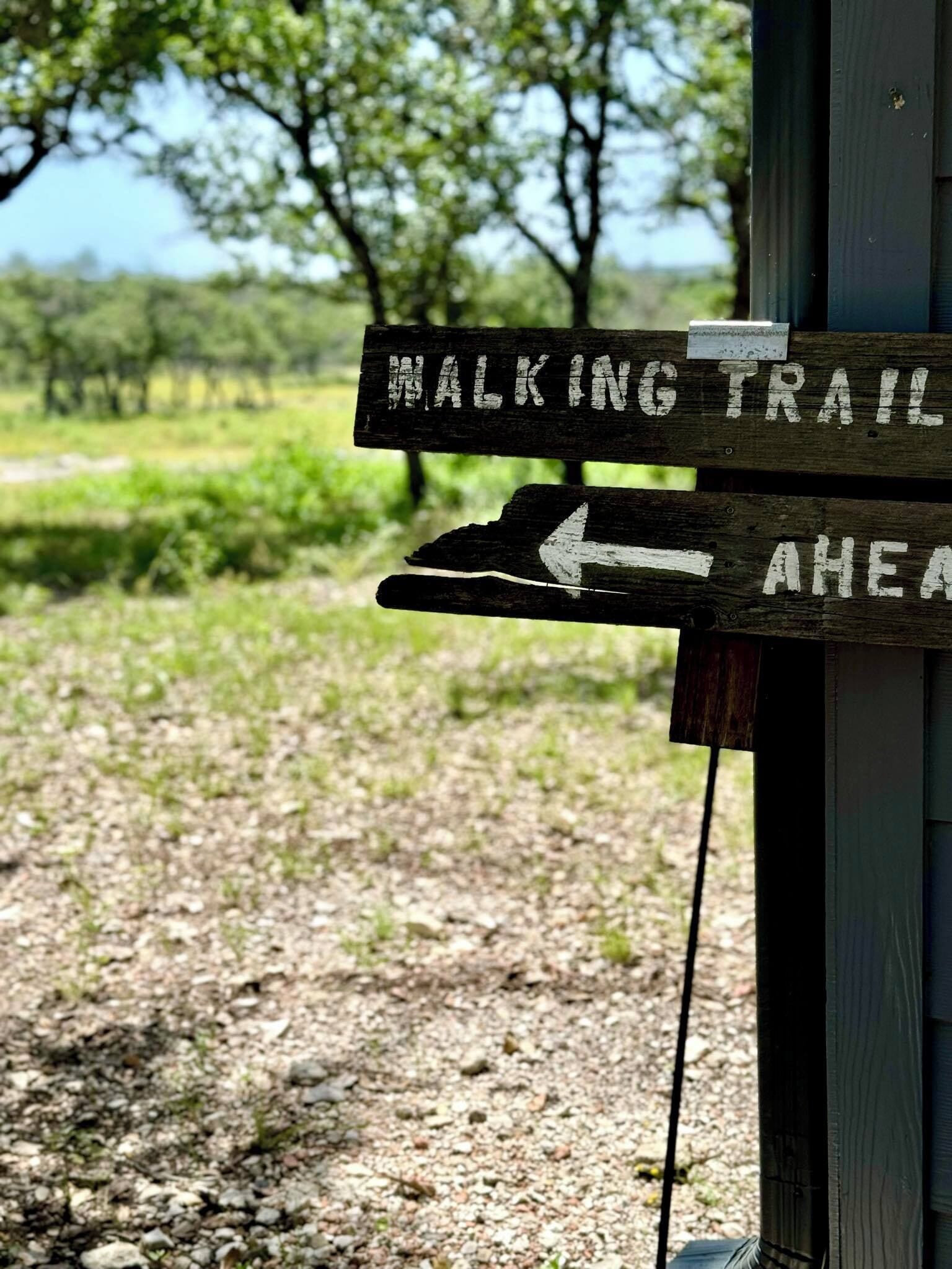 Un panneau en bois indiquant un sentier pédestre plus loin.