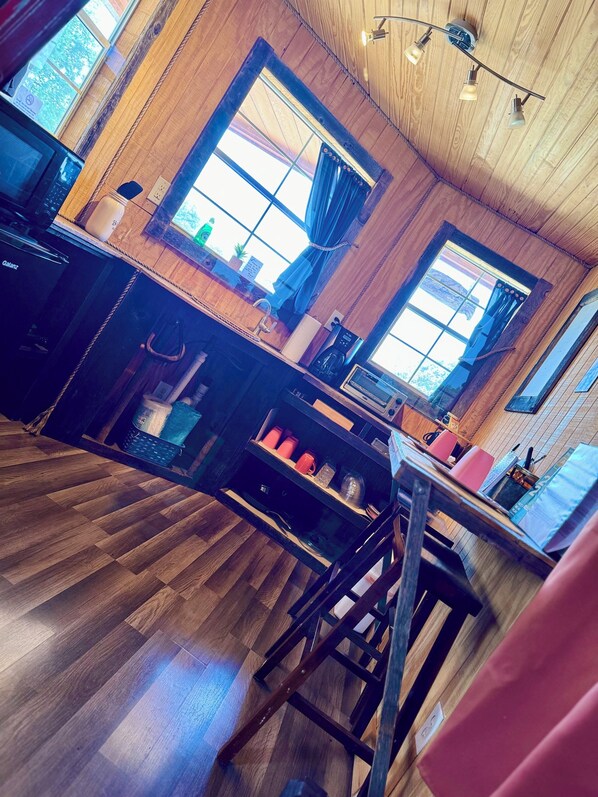 A cozy kitchen with wooden floors, a central island, and large windows. - Cowboys and Angels Retreat (Mountain Home)