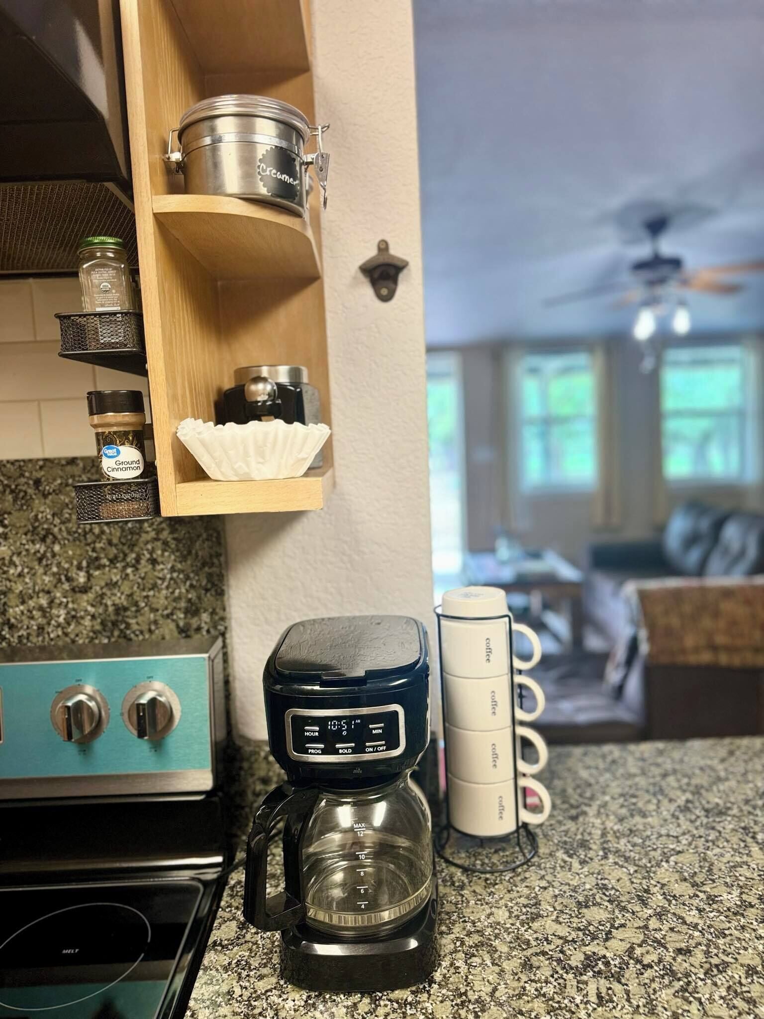 Une cuisine équipée d’une machine à café, d’une cuisinière et d’étagères remplies de bocaux.