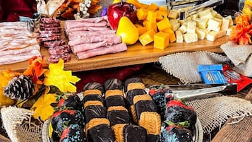 Eine Auswahl an Speisen, darunter Fleisch, Käse und Erdbeeren in Schokolade, präsentiert auf einem Holztisch.