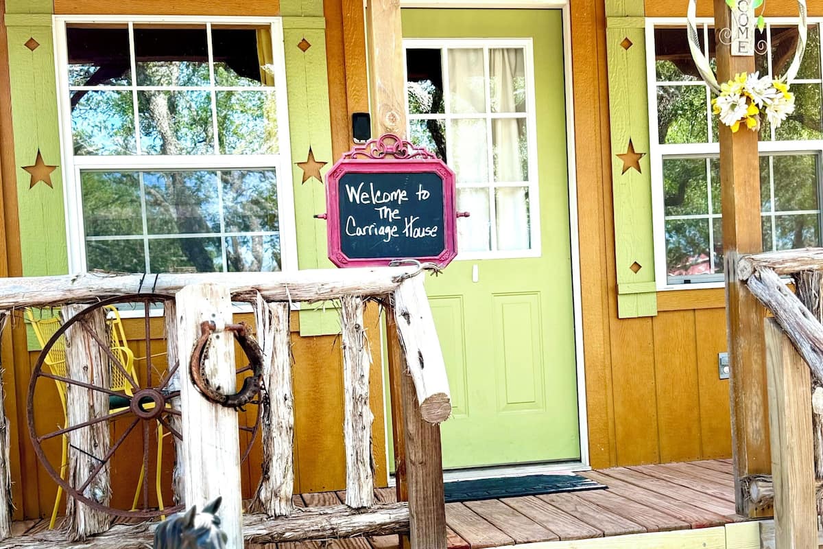 A wooden building with a sign reading "Welcome to the Carriage House."
