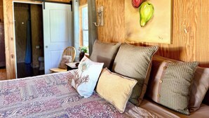 Una stanza accogliente con soffitto in legno, copriletto decorato e un quadro appeso al muro raffigurante pere.