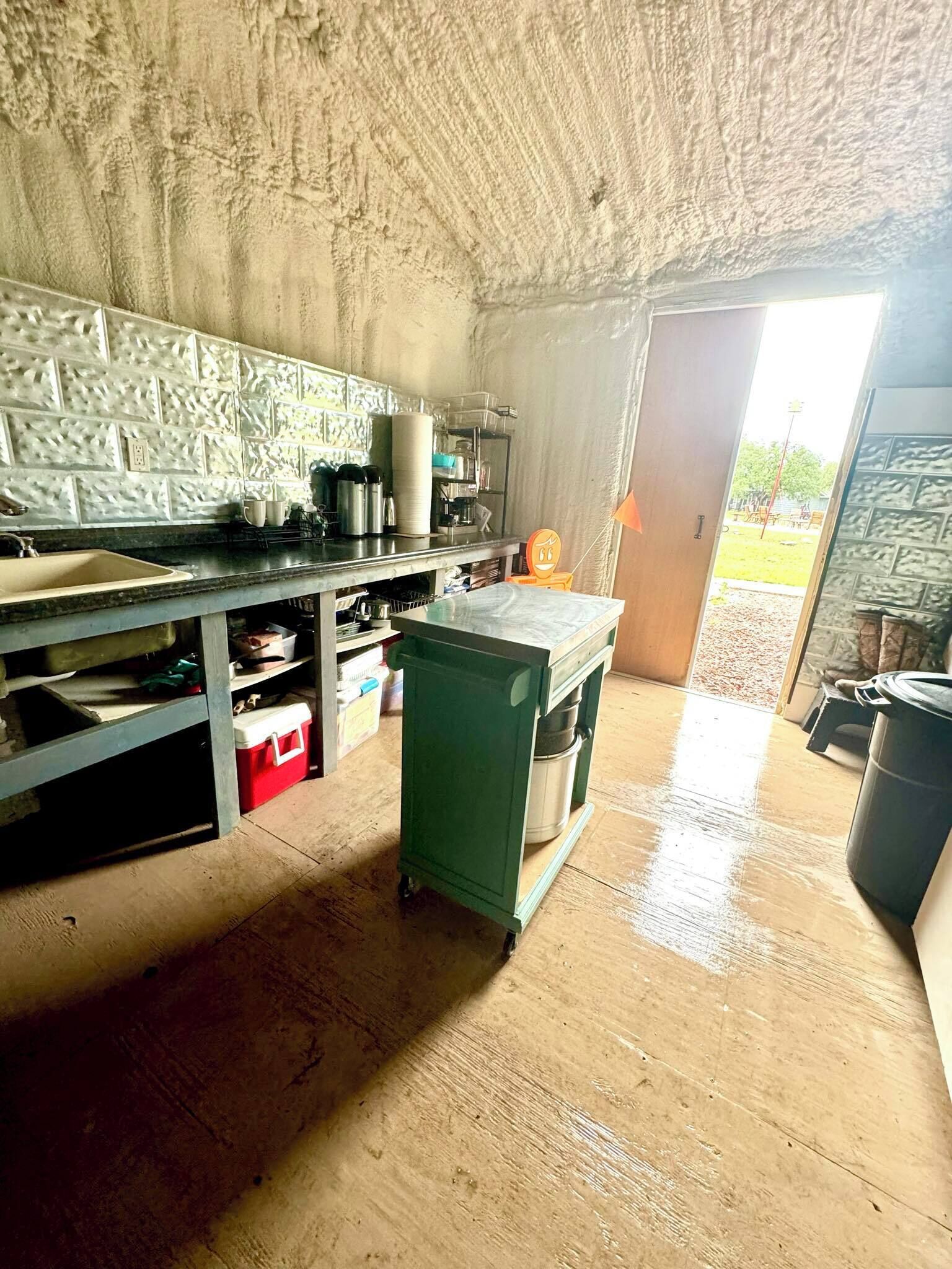 Une cuisine de taille réduite, dotée d’un plan de travail carrelé, d’un évier et d’un comptoir sur lequel sont disposés divers ustensiles de cuisine.