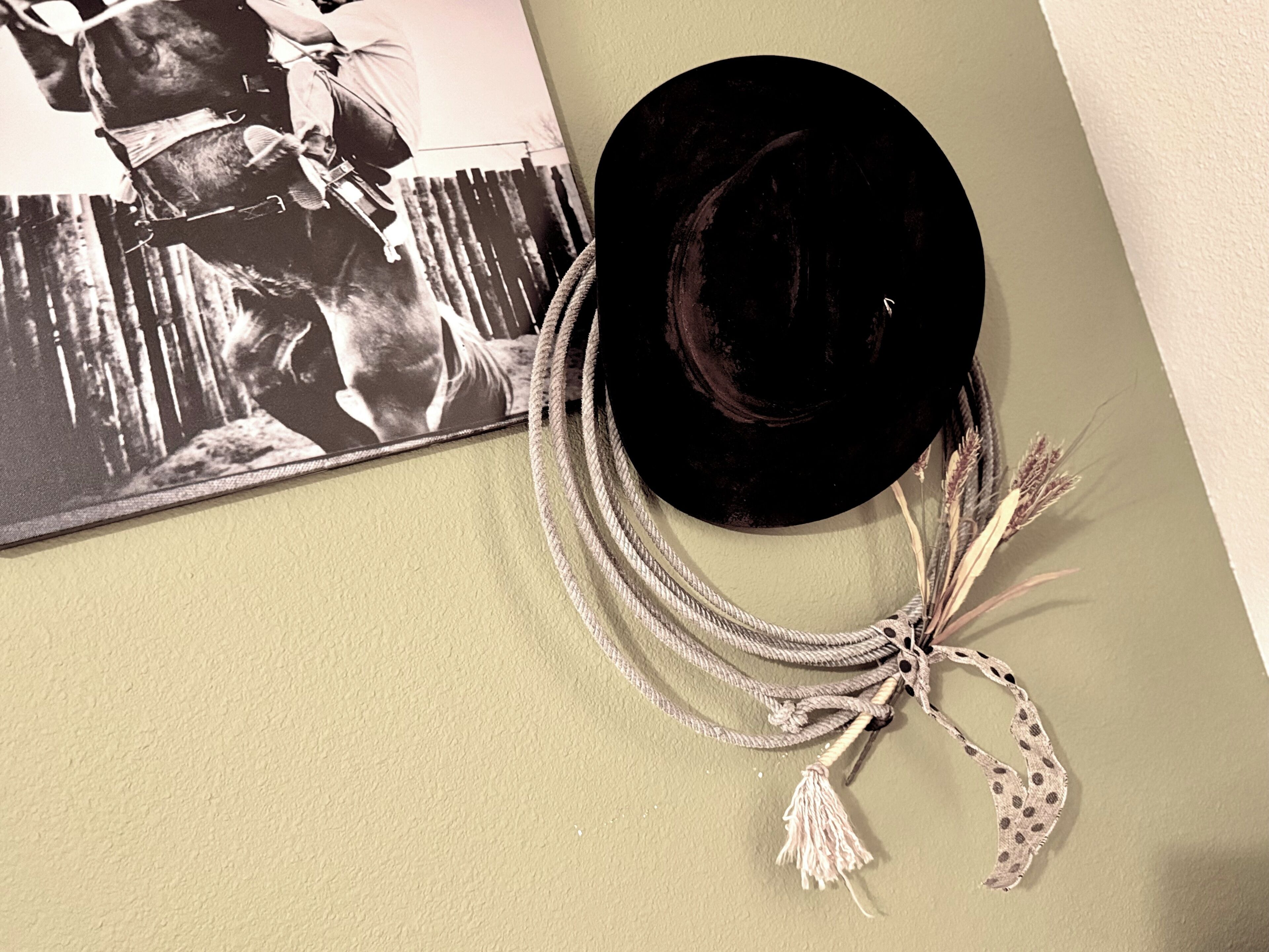 A black hat with a tassel and a rope accessory on a wall.