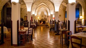 A restaurant with a high arched ceiling, tiled floor, and tables set for dining. - Albergo Masseria Gattamora (Uggiano la Chiesa)
