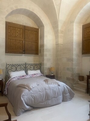 A bedroom with a bed, two nightstands, a lamp, and wooden cabinets. - Albergo Masseria Gattamora (Uggiano la Chiesa)