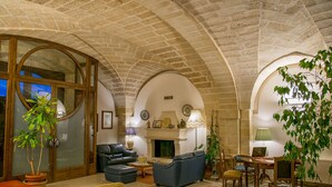 A spacious living room with a fireplace, leather sofas, and a dining area. - Albergo Masseria Gattamora (Uggiano la Chiesa)