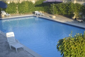 A swimming pool with clear blue water, surrounded by stone tiles and white lounge chairs. - Albergo Masseria Gattamora (Uggiano la Chiesa)