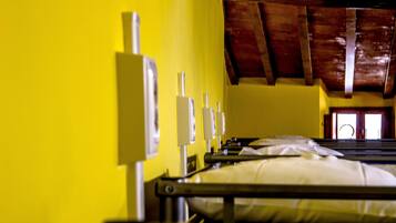 Una habitación con paredes amarillas, vigas de madera en el techo y una cama con ropa blanca.