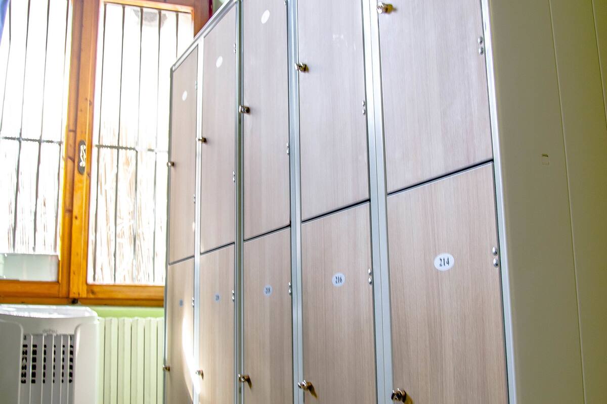 A room with a large wooden wardrobe, a radiator, and a window with bars.