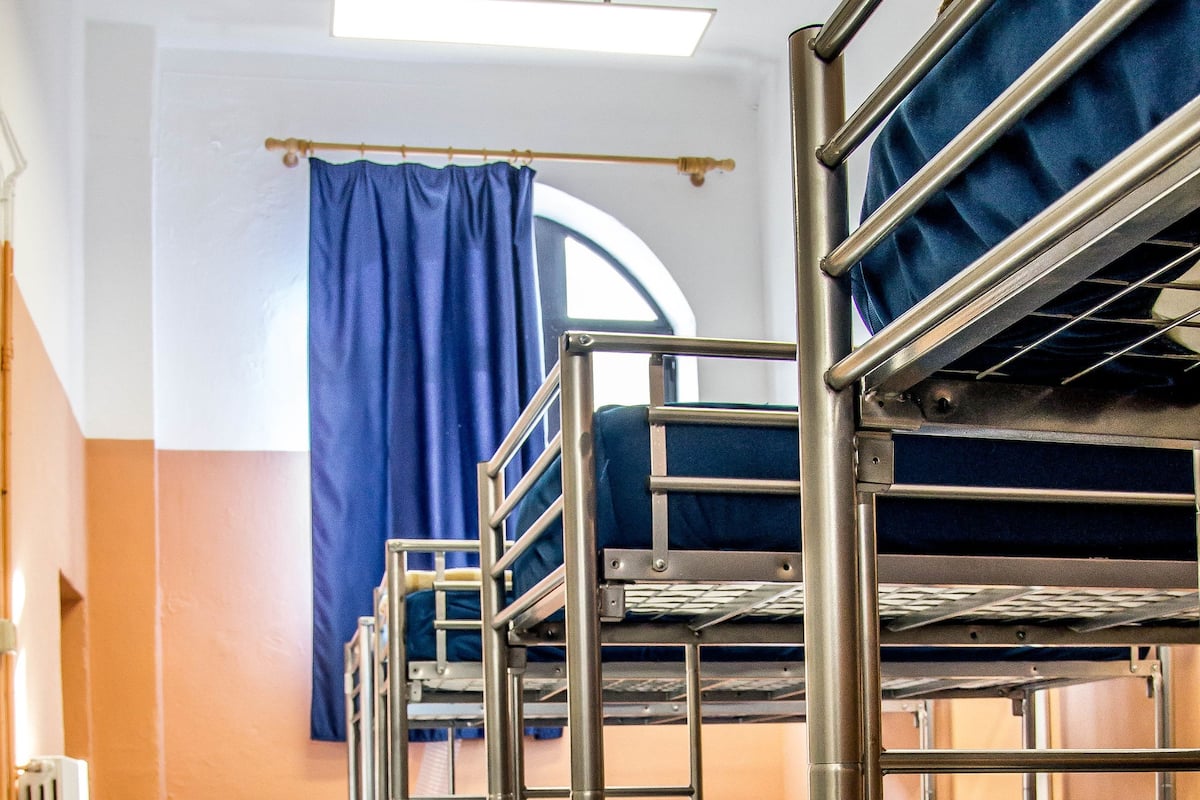 A bunk bed room with a heater, a window with curtains, and a radiator.