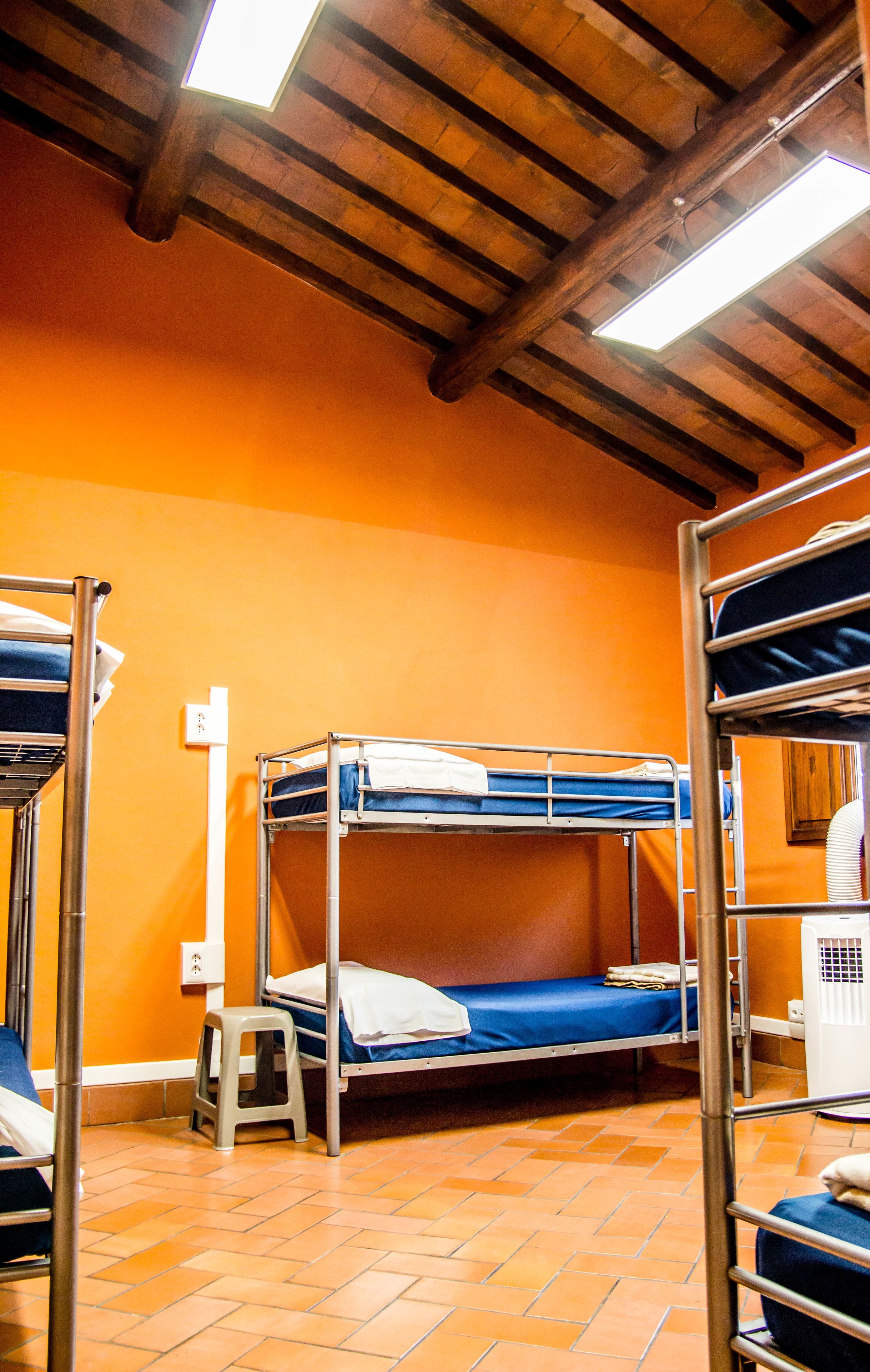 Un dormitorio con literas, paredes naranja y suelo de baldosas.