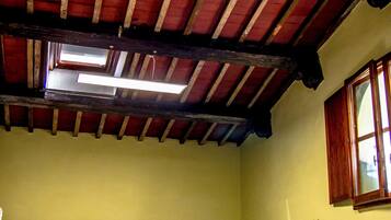A dormitory room with bunk beds, a ceiling fan, and a window.