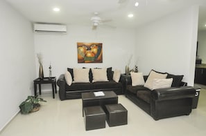 A modern living room with two black sofas, a coffee table, and decorative vases.