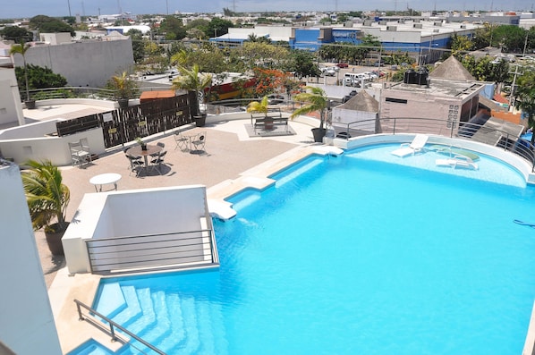 A rooftop swimming pool with lounge chairs and a small deck area.