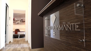 Uma área de recepção com design moderno, apresentando uma parede revestida de madeira e uma porta de vidro com o nome "DIMORAN DIAMANTE".