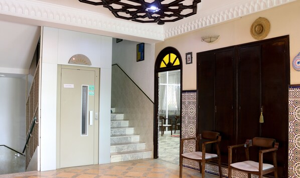 A hotel lobby with a staircase, a reception desk, and a decorative wall.