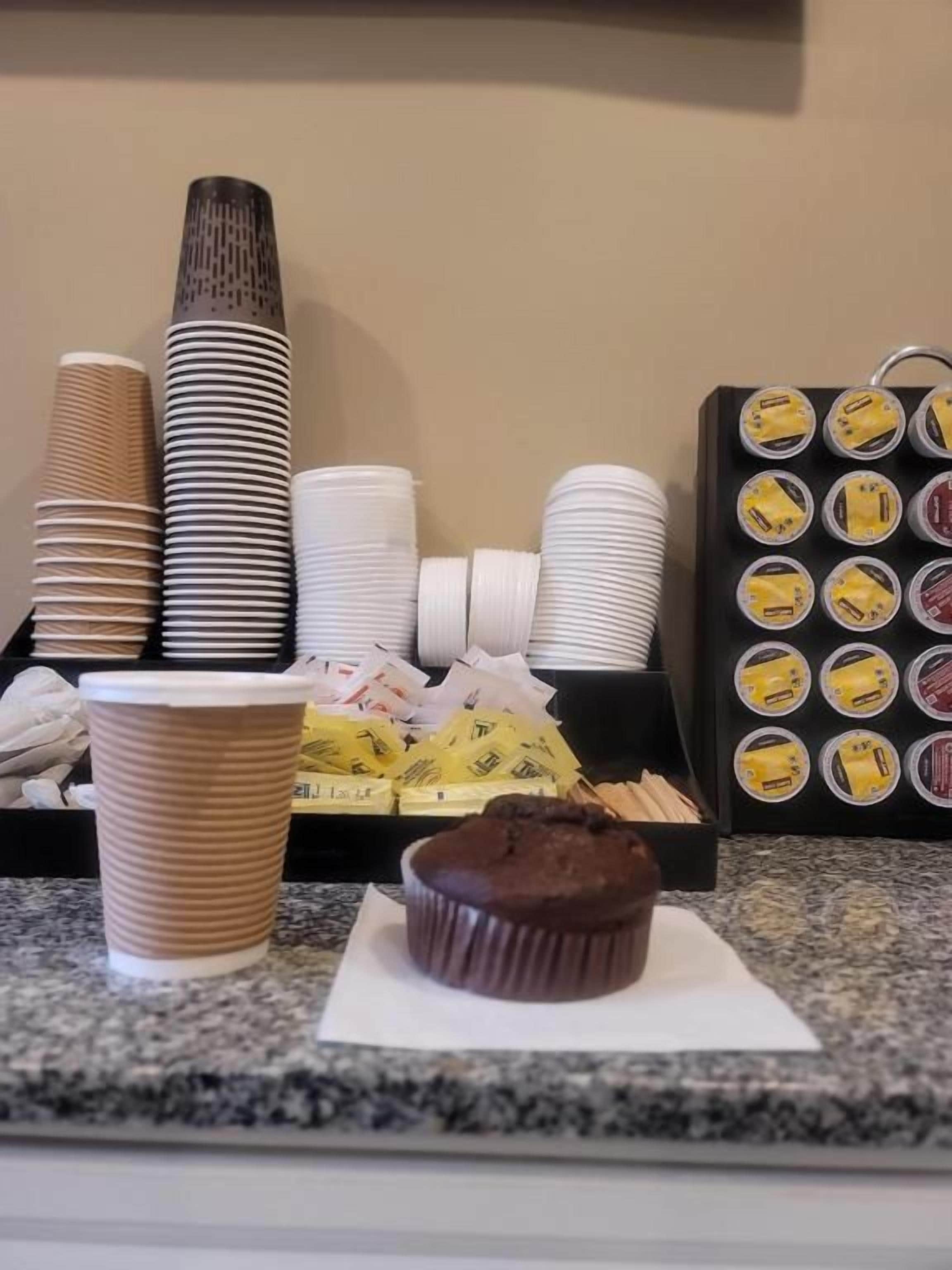 Een aanrecht met wegwerpbekers, een muffin en een schaal met verpakte etenswaren.