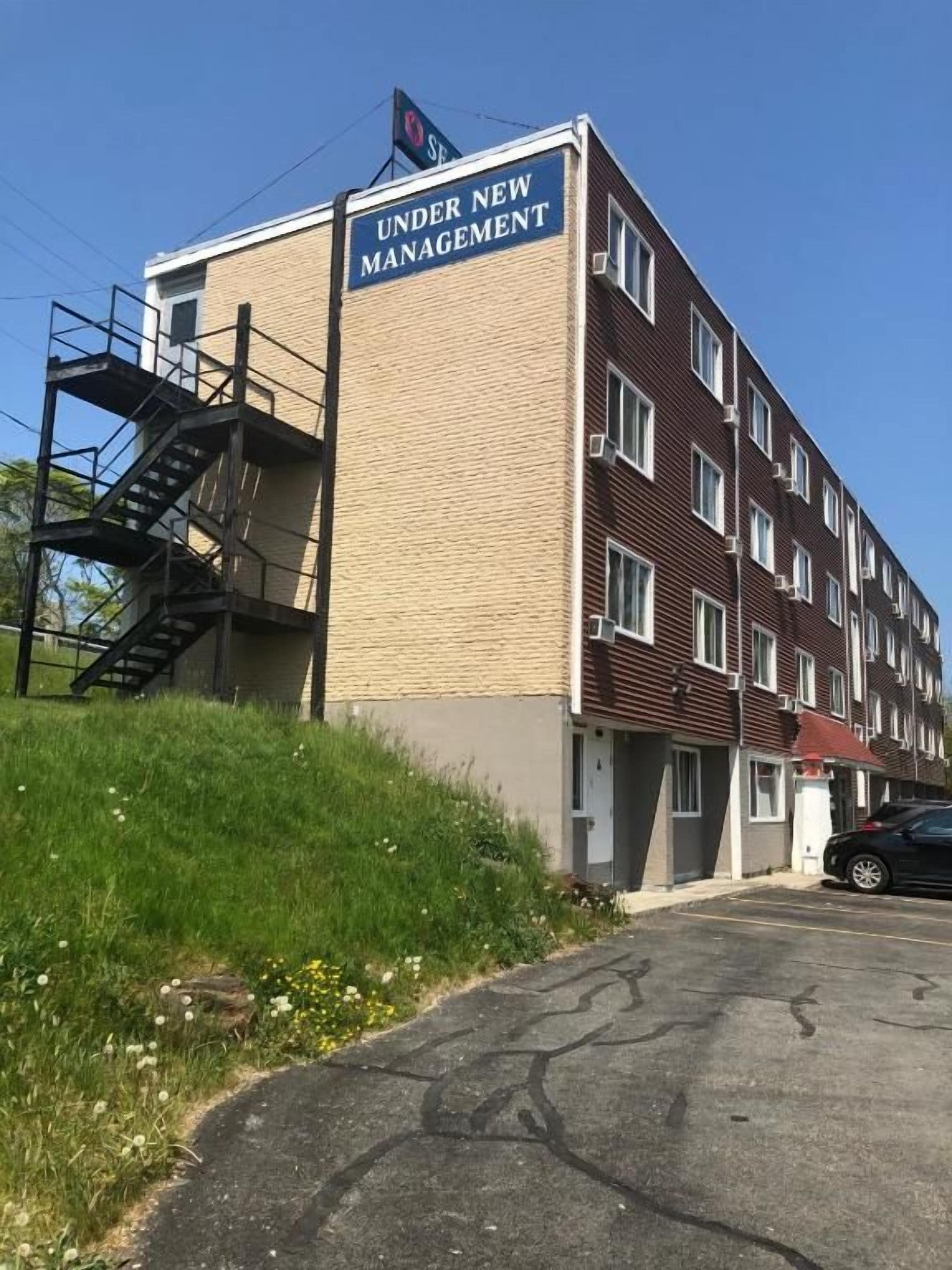 Un edificio de varios pisos con un cartel que dice 'BAJO NUEVA GESTIÓN'.