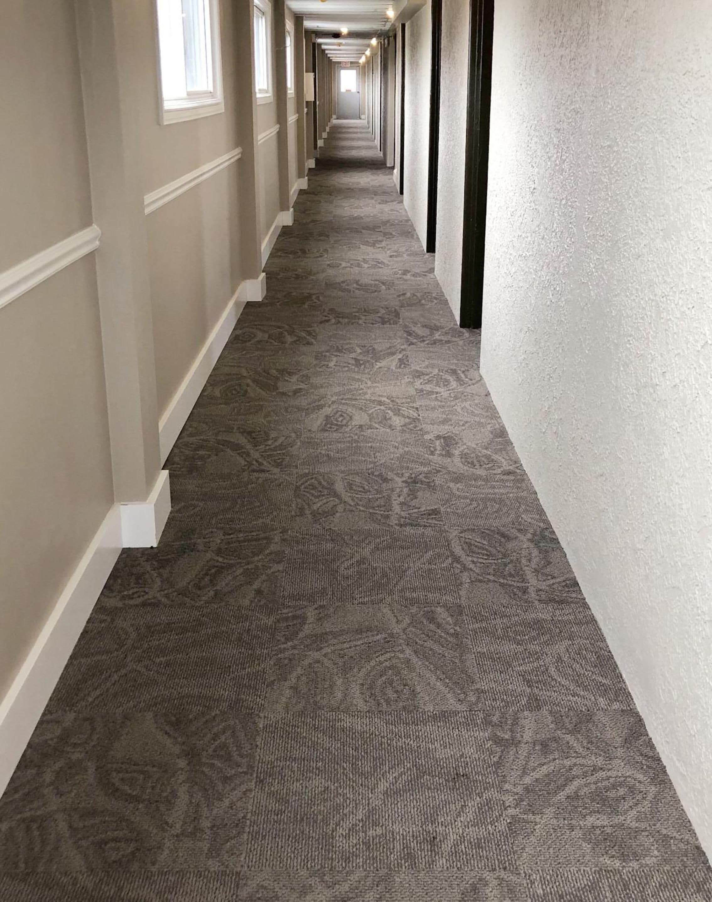 Un long couloir étroit, doté d’un tapis à motifs et de boiseries blanches.