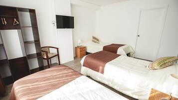 Habitación de hotel con dos camas, un armario, un televisor y una silla.