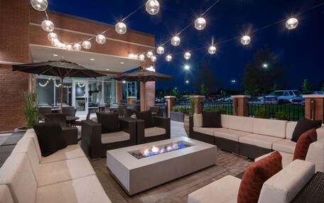 An outdoor seating area with sofas, a fire pit, and string lights.