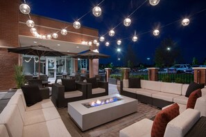 An outdoor seating area with sofas, a fire pit, and string lights. - Hyatt Place Denver/Westminster (Westminster)