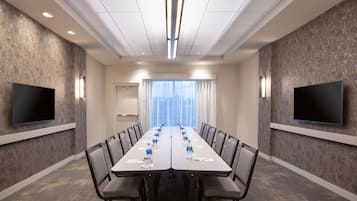 A conference room with a long table, chairs, and two flat-screen TVs on the walls.