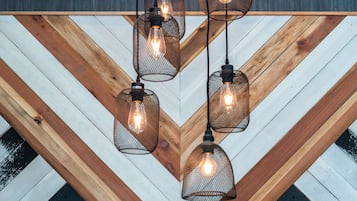 A ceiling with wooden beams and hanging wire mesh pendant lights.