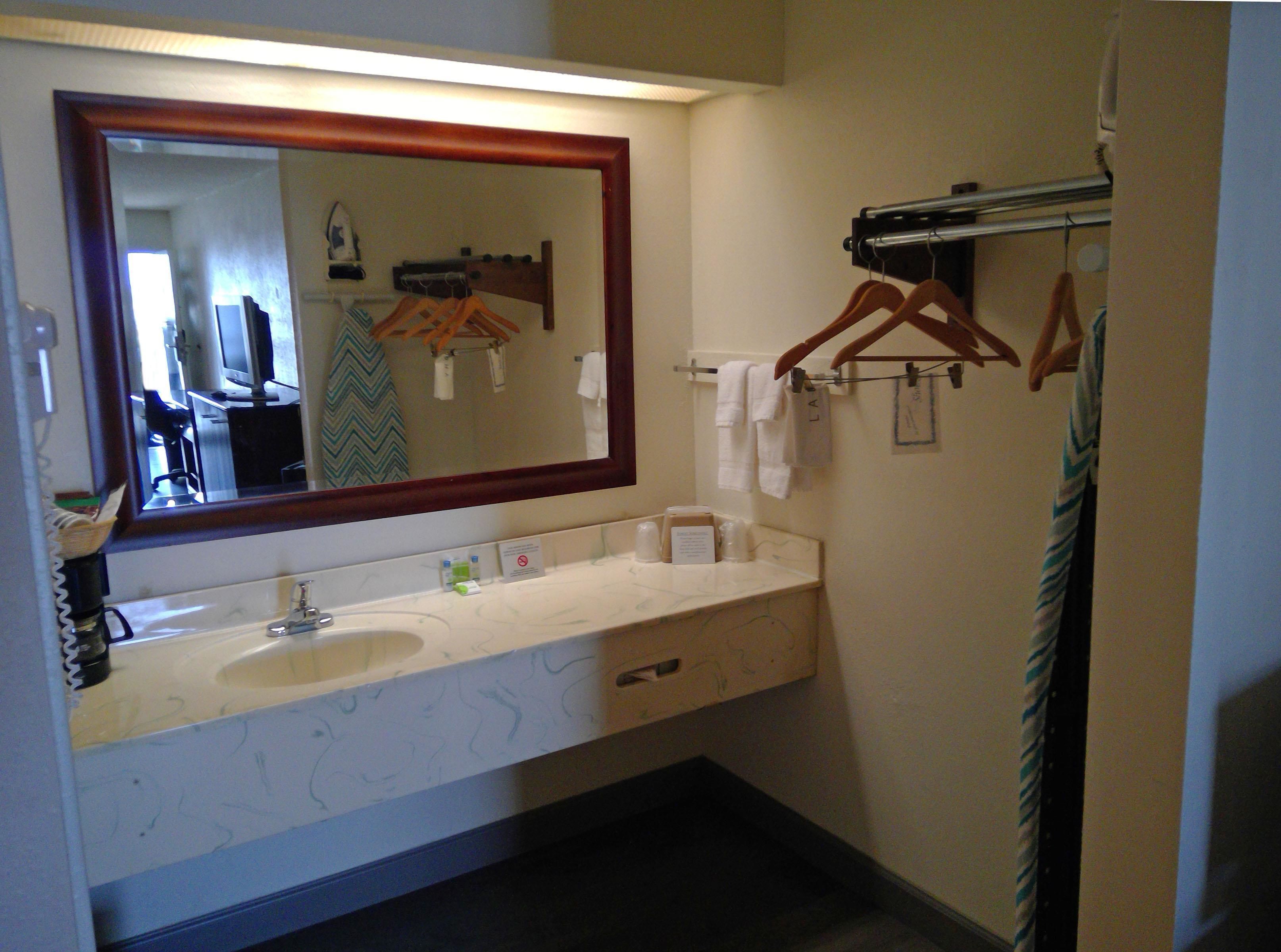 A bathroom with a large mirror, a sink, and a towel rack.