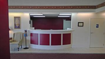 A reception area with a curved desk, a chair, a framed picture on the wall, and a door with a wheelchair accessibility sign.