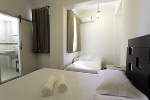 A hotel room with two beds, a bathroom, and a large mirror.