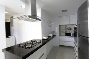 A modern kitchen with a black countertop, stainless steel appliances, and white cabinetry.