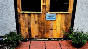 A wooden door with the sign 'BOTHY' above it and a welcome sign below. - Strathcarron Hotel (Strathcarron)
