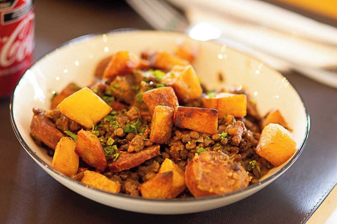A bowl of food with lentils and potatoes.