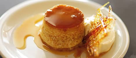 Un plato de postre con un flan de caramelo y una porción de helado, ambos bañados en salsa de caramelo.