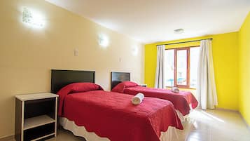 A room with two beds, a nightstand, and a window with curtains.