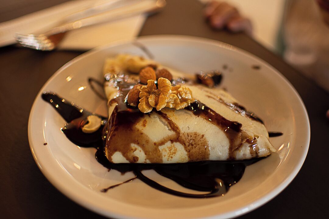 A dessert on a plate with chocolate sauce and nuts.