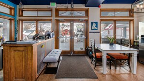 A restaurant interior with a wooden counter, bench seating, and large windows. - The Bunkhouse - Hostel (Minturn)