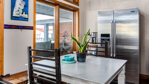 A kitchen with a stainless steel refrigerator, a dining table with chairs, and a potted plant. - The Bunkhouse - Hostel (Minturn)