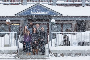 Um grupo de pessoas em frente a um edifício com uma placa que diz 'The bunkhouse'.
