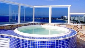 A hot tub with a panoramic ocean view, surrounded by stone walls and blue tiles. - LineBooking - Cobertura 3 Quartos - 360 (Rio de Janeiro)