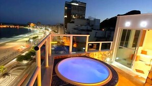A rooftop pool with a view of the beach and cityscape at dusk. - LineBooking - Cobertura 3 Quartos - 360 (Rio de Janeiro)