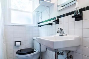 Un baño con lavamanos blanco, inodoro y ventana.