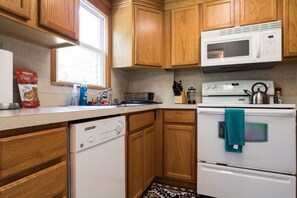A kitchen with wooden cabinets, a microwave, an oven, and a dishwasher.