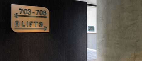 A sign indicating the location of the lifts with directional arrows and a phone number.