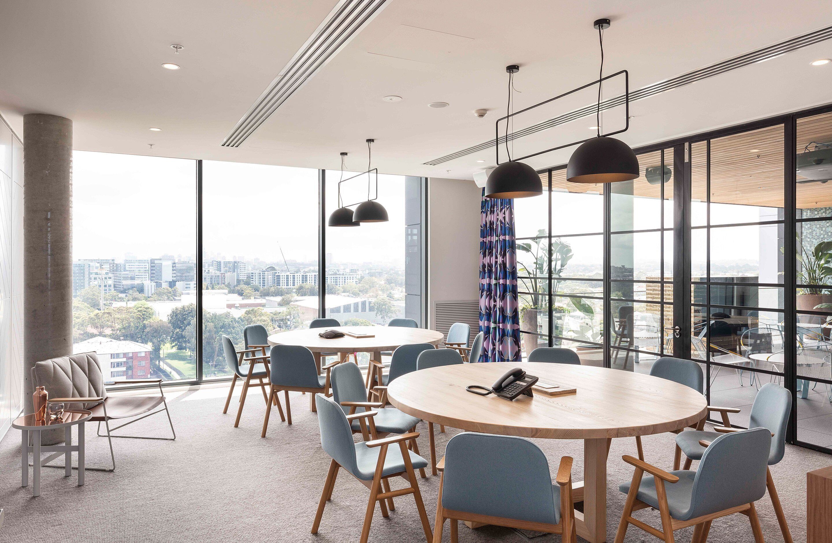 A conference room with large windows, round tables, and modern chairs.